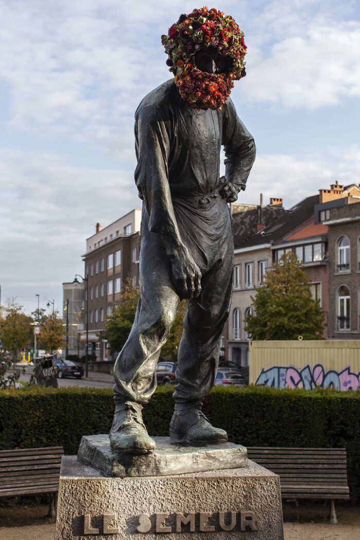 Bronze city statue dressed in vibrant flowers on the head, showcasing artistic floral decoration on urban sculpture.