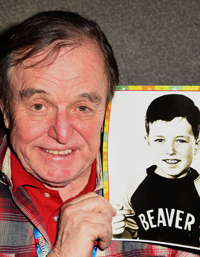 Older man holding a photo of his younger self from a beloved 50s show cast reunion, showing how much they’ve changed. Older man holding a photo of his younger self from a beloved 50s show cast reunion, showing how much they’ve changed.