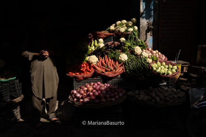 Street vendor selling fresh vegetables at a market, showcasing unseen realities of our world through photography.