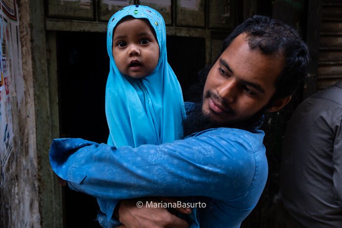Man holding baby girl dressed in blue, capturing unseen realities of our world through powerful photography.