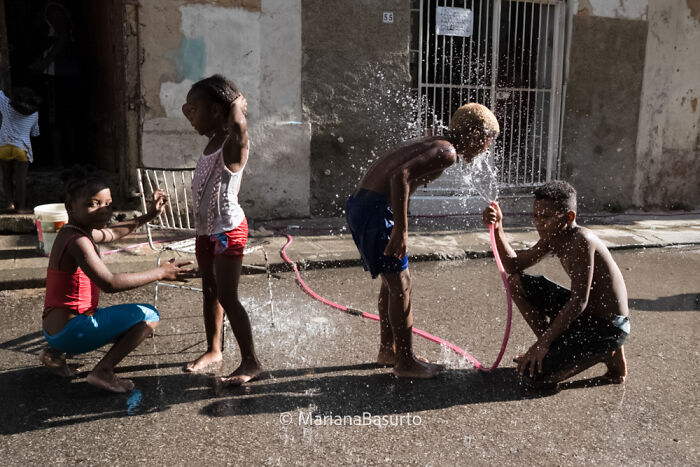 Children playing with water on a street, capturing unseen realities of our world through vibrant and candid photography.