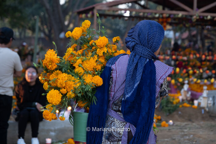 Photographer reveals unseen realities of a woman carrying vibrant orange flowers in a cultural outdoor setting.