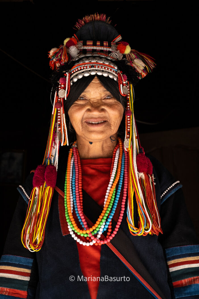 Elderly woman in traditional colorful attire and beadwork, captured by photographer revealing unseen realities of our world.