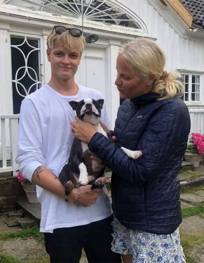 Young man holding a dog outside a house with a woman, related to Norwegian Crown Princess&rsquo;s son charges news.