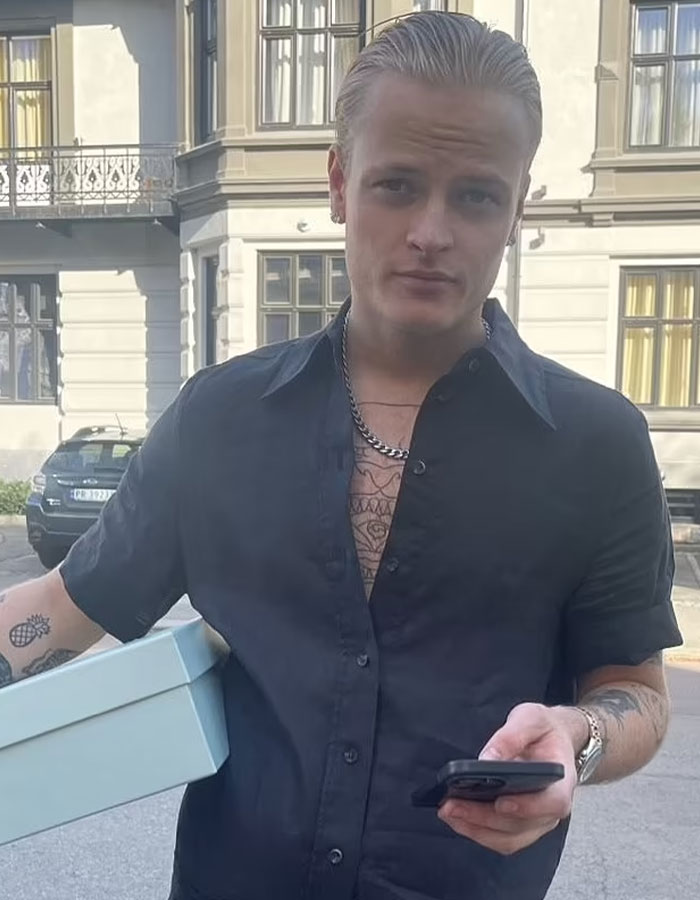 Young man outdoors, holding a box and phone, representing Norwegian Crown Princess&rsquo;s son facing charges including violent assaults.