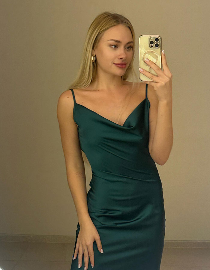 Young woman in a green satin dress taking a mirror selfie related to ex-model and influential family ties in Dubai case.