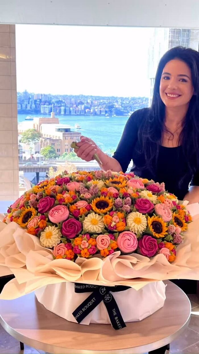 Woman smiling next to an elaborate baked goods bouquet designed to look like a colorful flower arrangement.