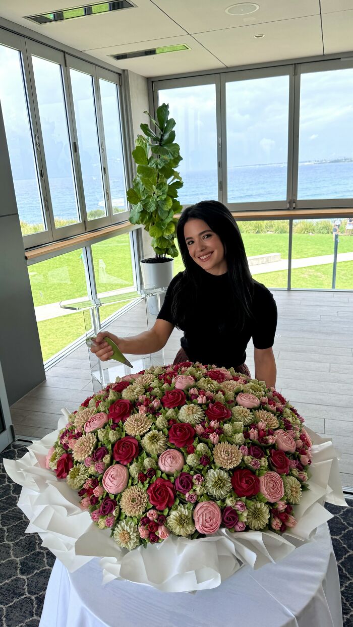 Artist creating intricate baked goods that look like a flower bouquet with roses and various floral designs on a table.