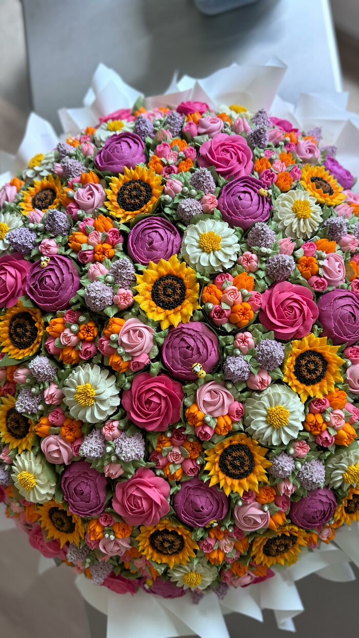 Colorful bouquet of baked goods decorated to look like blooming flowers in vibrant pinks, yellows, whites, and greens.