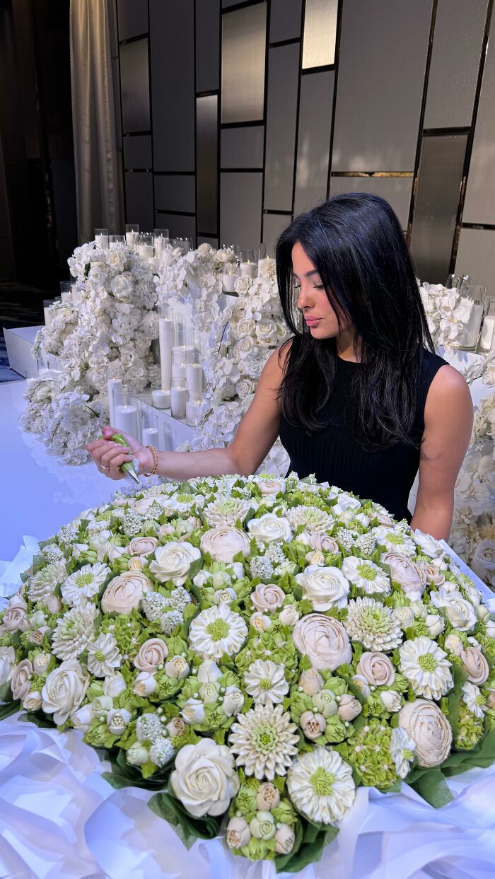 Woman decorating green and white baked goods that look like flower bouquets with icing in an elegant setting