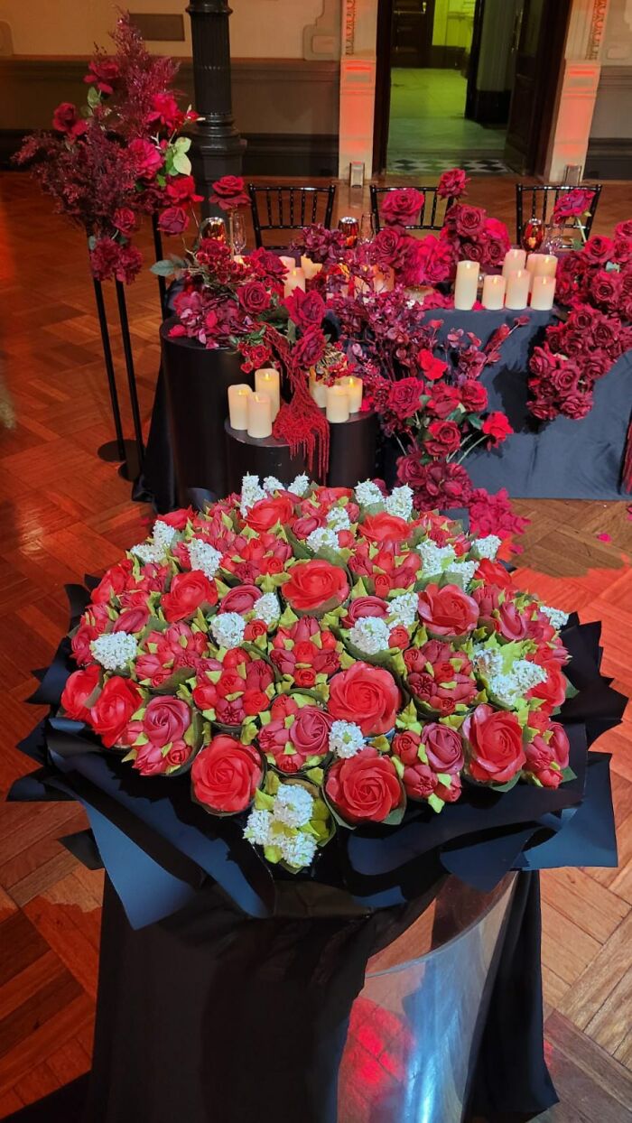 Large bouquet of baked goods resembling flower bouquets with red and white floral designs displayed indoors.