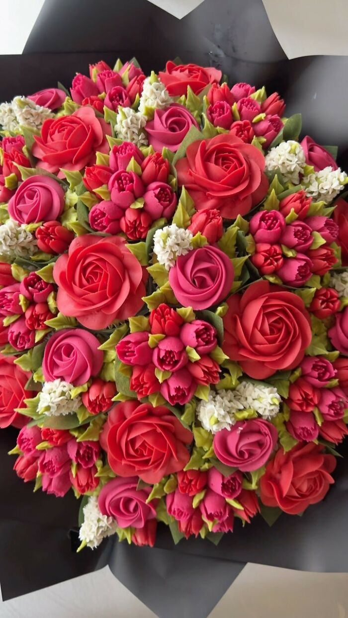 Bouquet of baked goods designed to look like vibrant pink and red flower bouquets with green leaves.