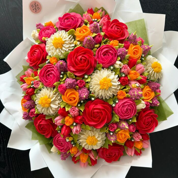 Colorful baked goods bouquet with rose and daisy designs, showcasing creative cupcake art resembling flower bouquets.