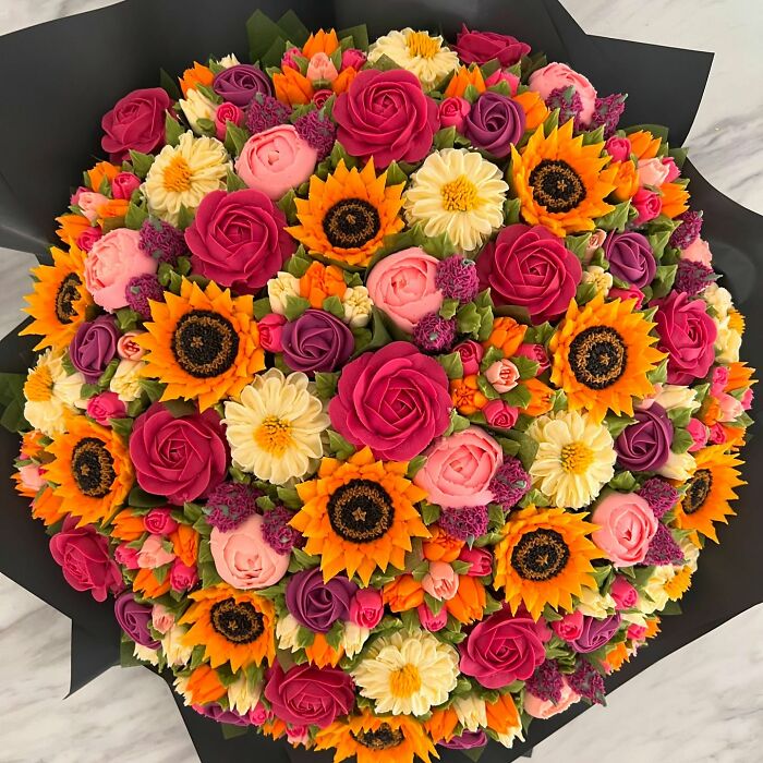 Colorful cupcake bouquet resembling a vibrant flower bouquet with sunflowers, roses, and various baked flower designs.
