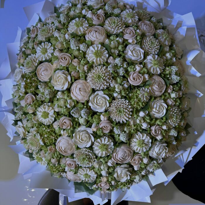 Bouquet of baked goods crafted to look like delicate flowers in soft green and cream tones by a skilled artist.