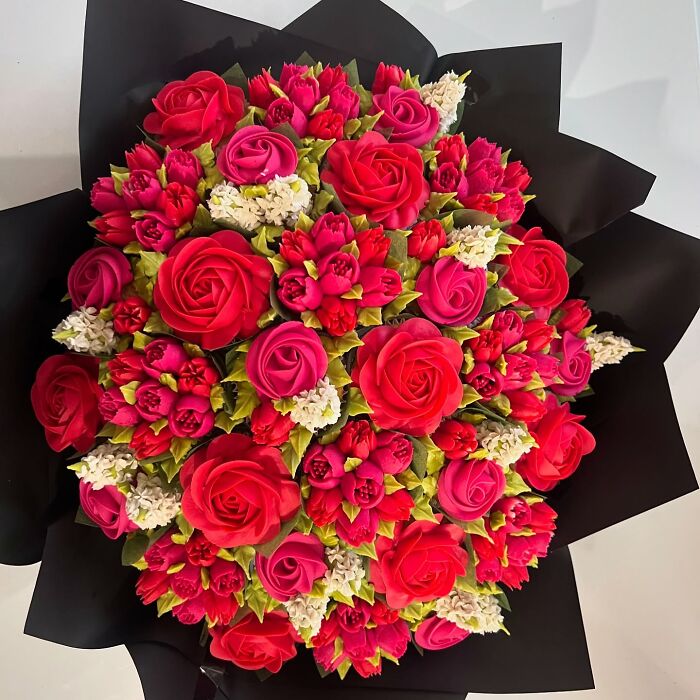 Bouquet of red and pink cupcakes designed to look like flower bouquets with green leaves and white accents.