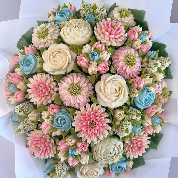 Bouquet of baked goods crafted to resemble flower bouquets with pink, blue, and cream floral designs by an artist.