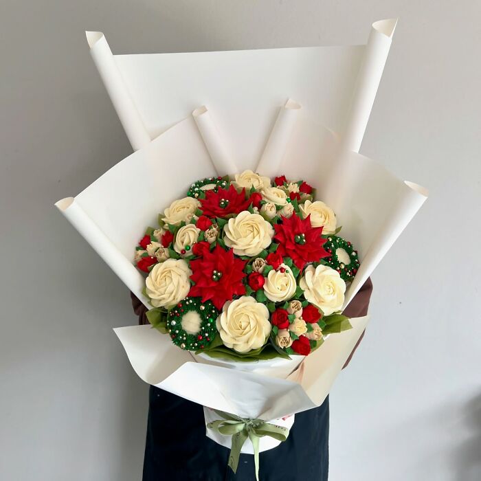 Bouquet of baked goods resembling flowers with intricate red and cream frosting, showcasing creative cupcake art design.
