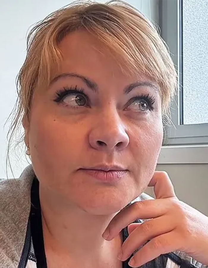 Model brutally attacked in Dubai with a thoughtful expression, looking away, sitting indoors near a window.