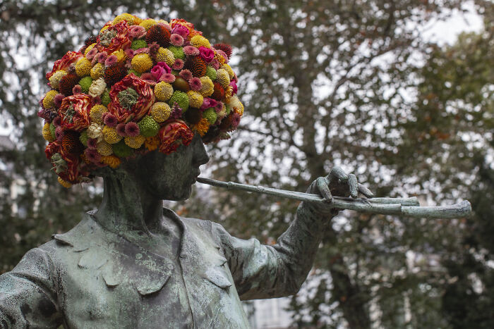 City statue dressed in vibrant flowers with a floral headdress, showcasing artistic flower decorations on urban sculptures.