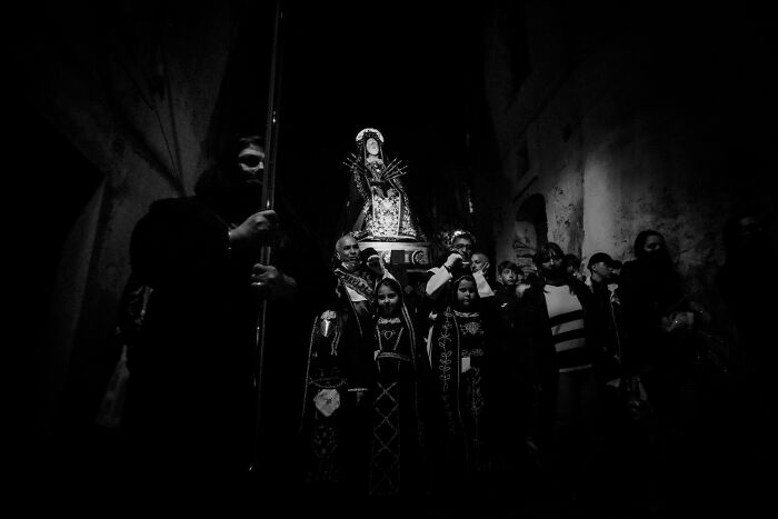 Black and white cinematic photo of a religious procession at night capturing dramatic light and shadows.