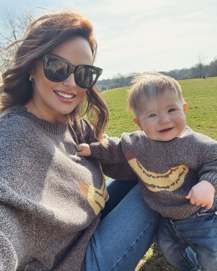 Model with F-cup chest wearing sunglasses outdoors with a toddler, highlighting breast reduction surgery journey.