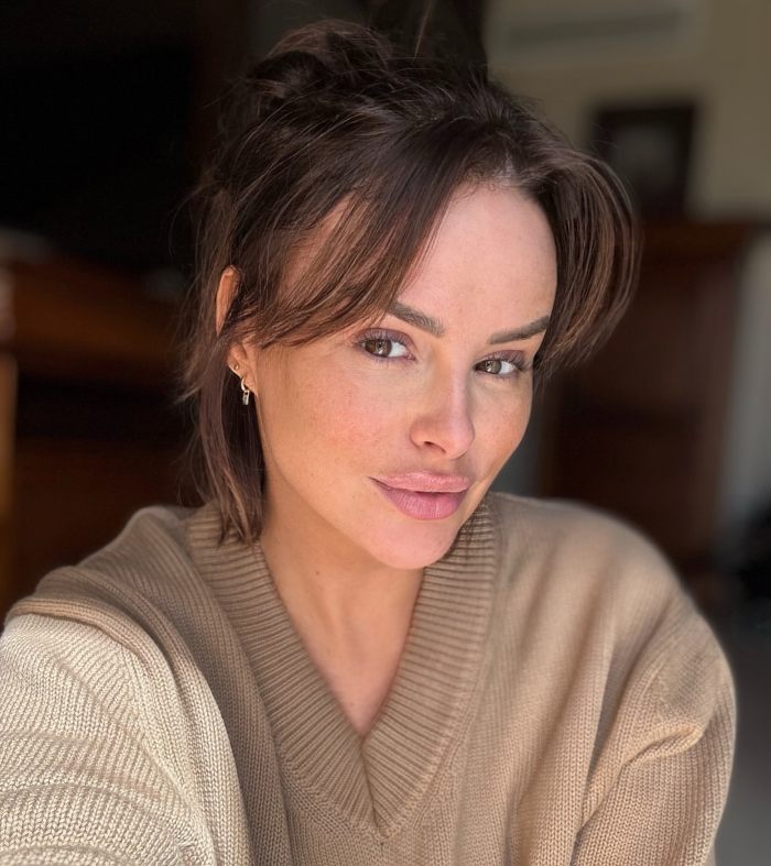 Model with F-cup chest posing indoors wearing a beige sweater after breast reduction surgery recovery.