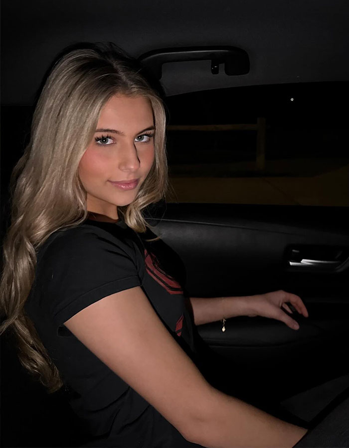 Young woman sitting in a car at night, representing nepo grandbaby involved in a song directed by mom.