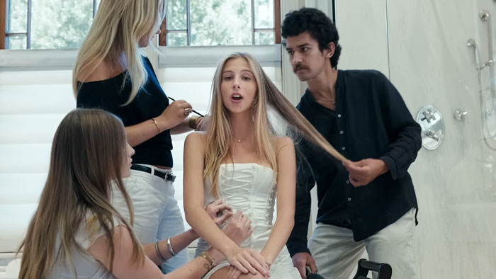 Young woman labeled nepo grandbaby being styled by team while filming a music video about luxurious life complaints directed by mom