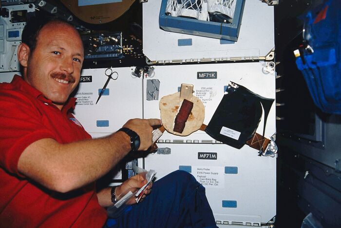 Astronaut in space station preparing food, illustrating intriguing and bizarre astronaut facts that might surprise you.