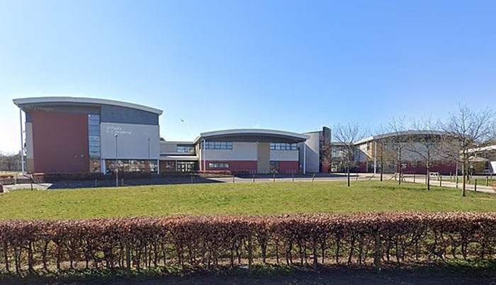 Modern school building with a large green lawn, related to teen who brutally slammed teacher head-first into concrete case.