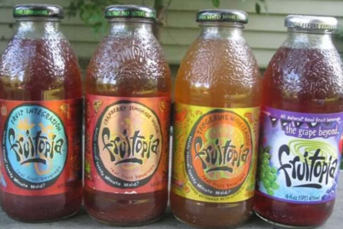 Bottles of discontinued Fruitopia beverages in various fruity flavors lined up outdoors on a table.