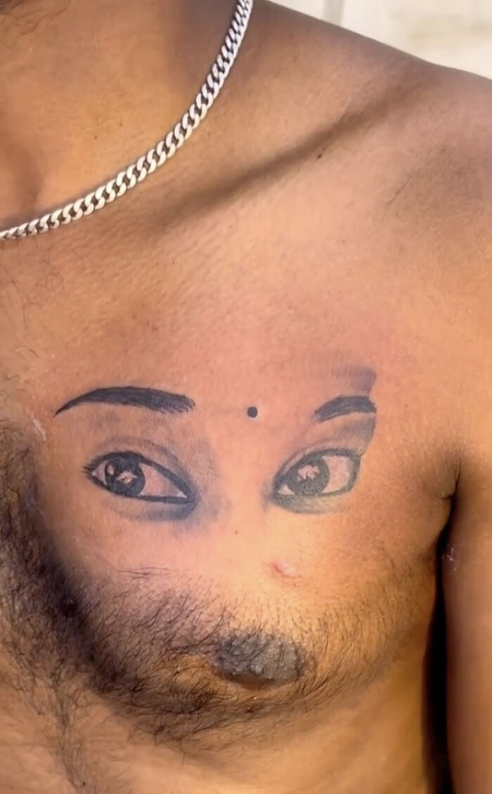 Close-up of bizarre tattoo with realistic eyes inked on a man's chest, blending with chest hair in an unusual design choice.