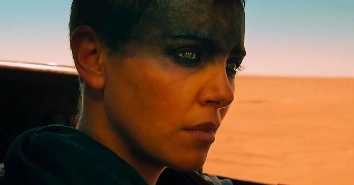 Close-up of a person with dark eye makeup looking focused in a desert landscape, representing films from the new millennium.