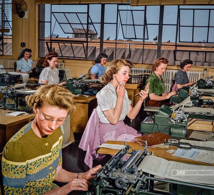 Women working in an office with typewriters in a colorized historical photo by a talented viral artist.