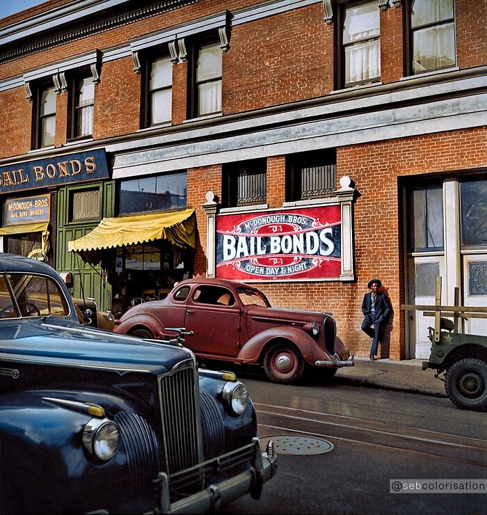 Colorized historical photo showing vintage cars parked by a McDonough Bros Bail Bonds building on a sunny street.