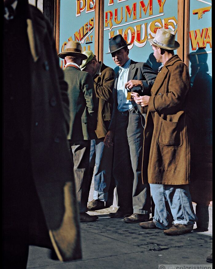 Group of men wearing hats and coats standing outside a building, colorized historical photo by a viral artist.