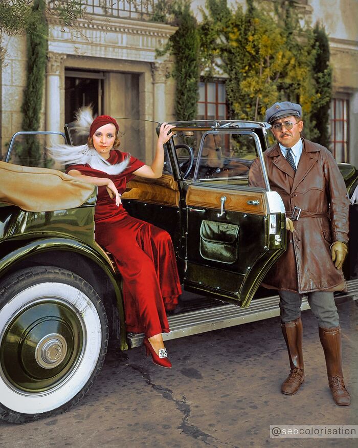 Colorized historical photo of a woman in red dress and a man in leather jacket by a vintage car, showcasing magical colorized art.