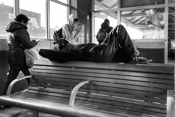 Black and white street photo showing Chicago locals at a transit stop, capturing the city's intimate urban life and soul.