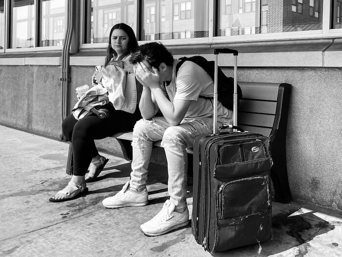 Two people seated on a bench in Chicago, one covering his face, captured in an intimate street photo capturing the city’s soul.