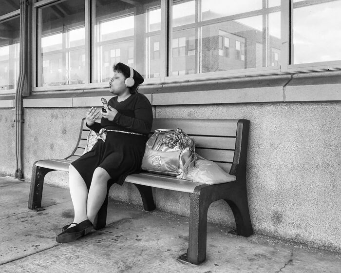 Woman wearing headphones sits on bench in Chicago street photo capturing the city’s soul through intimate urban moments.