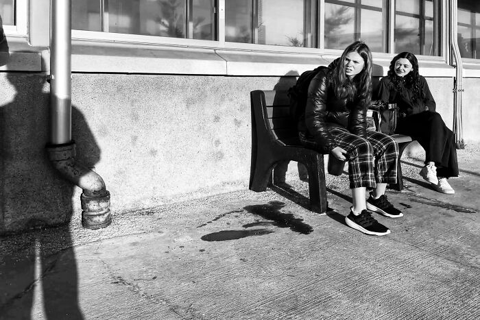 Two women sitting on a bench on a city street, part of intimate Chicago street photos capturing the city's soul.