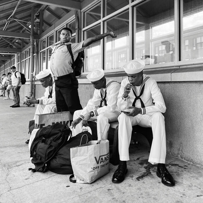 Young men in sailor uniforms and casual clothes waiting on a city sidewalk in a Chicago street photo capturing the city’s soul.