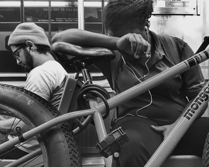 Black and white street photo capturing intimate moment of two people with a bike in Chicago public transit.