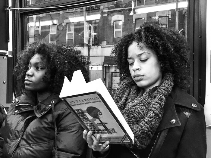Two women with curly hair on a Chicago street, one reading a book, capturing intimate street photos of the city’s soul