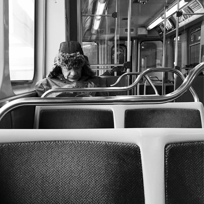 Man wearing winter hat sitting alone on Chicago street train, a moment from intimate street photos capturing the city’s soul.