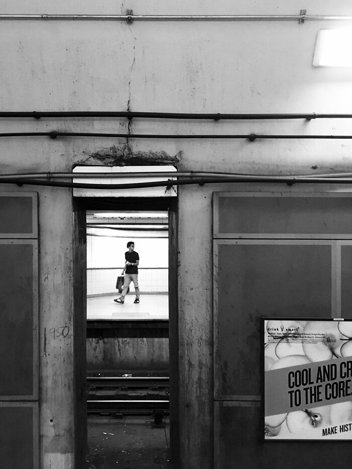 Black and white intimate Chicago street photo capturing a solitary person walking at an urban subway station platform.