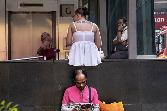 Candid street photo showing diverse people engaged in quiet moments of everyday life in an urban setting.
