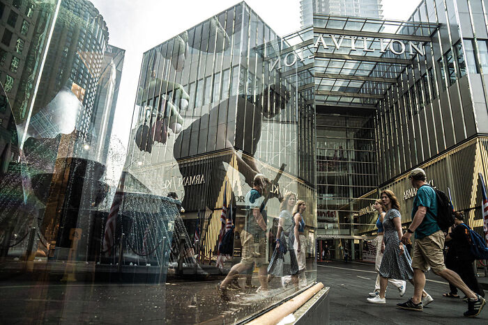 Candid street photo capturing the quiet beauty of everyday life with reflections in a modern urban shopping area.