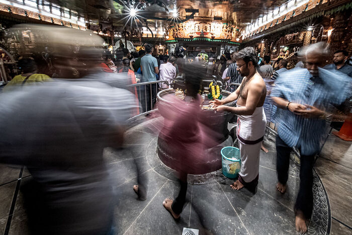Candid street photo capturing the quiet beauty of everyday life in a busy indoor market with blurred motion and vibrant activity.